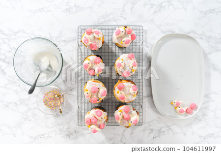 Decorating mini Easter bread kulich with sprinkles and meringue bird-shaped cookies. Decorating mini Easter bread kulich with sprinkles and meringue bird-shaped cookies. 104611997