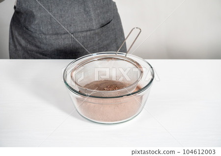 Sifting ingredients through hand sifter to make homemade hot chocolate mix. Sifting ingredients through hand sifter to make homemade hot chocolate mix. 104612003