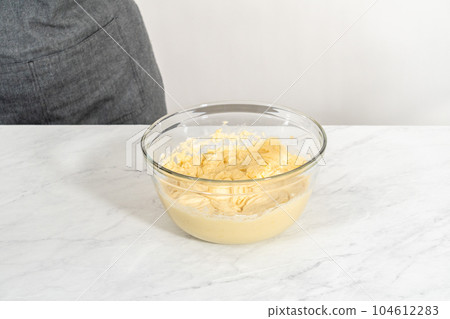 Mixing ingredients in a large glass mixing bowl to bake lemon blueberry bundt cake. 104612283