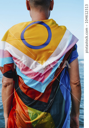 person wrapped in a progress pride flag in the sea 104612313