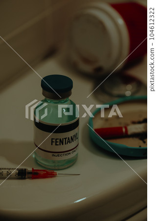 syringe and simulated vial of fentanyl on a toilet syringe and simulated vial of fentanyl on a toilet 104612322