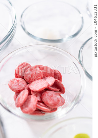 Measured ingredients in a glass mixing bowl to prepare hot chocolate bombs. 104612331