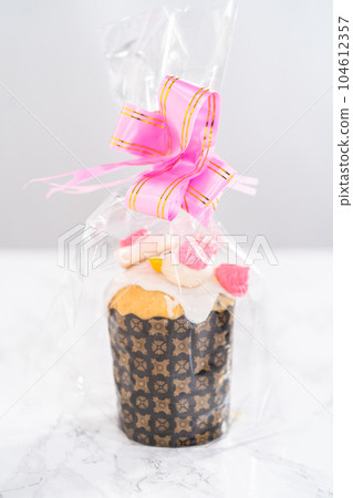 Wrapped mini Easter bread kulich with lemon glaze, decorated with sprinkles and meringue bird-shaped cookies as a good gift. Wrapped mini Easter bread kulich with lemon glaze, decorated with sprinkles and meringue bird-shaped cookies as a good gift. 104612357