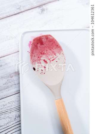 Dirty silicone spatula on a white board on the kitchen counter. Dirty silicone spatula on a white board on the kitchen counter. 104612361