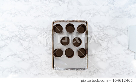 Scooping bread dough into paper liners to bake mini Easter bread kulich. Scooping bread dough into paper liners to bake mini Easter bread kulich. 104612405