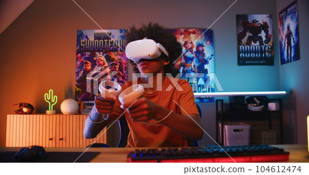 Teenage gamer in VR headset plays virtual online video game 104612474