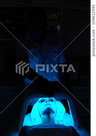 Woman getting facial treatment with led therapy. 104612495