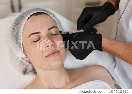 woman receives cosmetic botox injection in face. 104612511