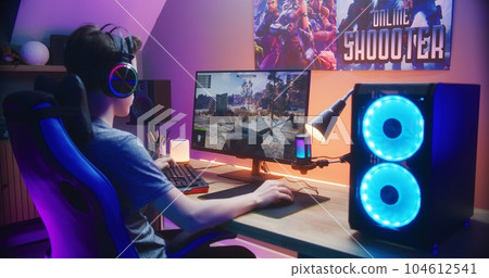 Young gamer controls tank while playing game on PC 104612541