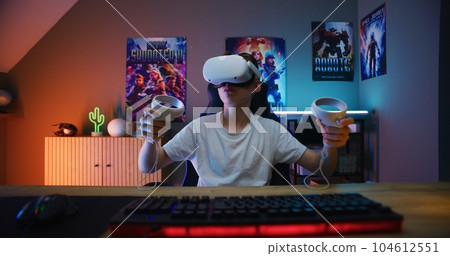 Young gamer in VR headset plays virtual online video game 104612551