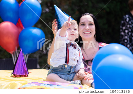 birthday celebration for a little gentleman, celebrates his first-year with his mother. Balloons, party hats, and a variety of birthday decorations birthday celebration for a little gentleman, celebrates his first-year with his mother. Balloons, party hats, and a variety of birthday decorations 104613186