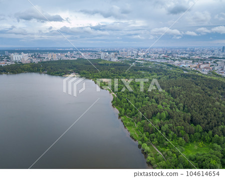 Big lake with green shores in bright sun light and city on horizon, aerial landscape. Recreation concept. Aerial view 104614654