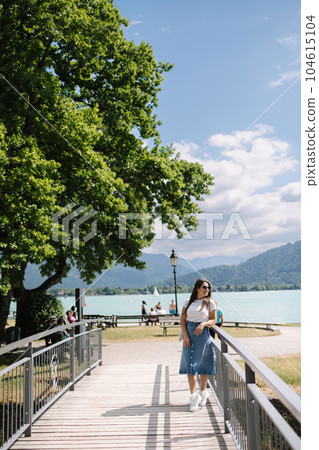 Elegant woman in denim skirt walking though the little bridge and smile. Stylish female Elegant woman in denim skirt walking though the little bridge and smile. Stylish female 104615104