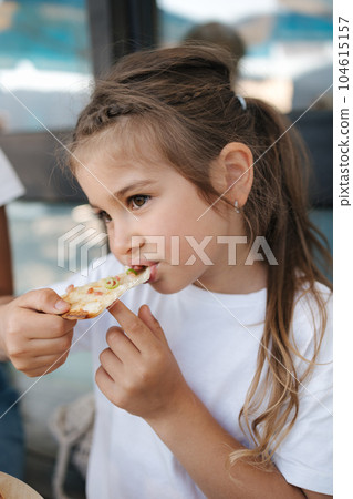 Little girl eating pizza in cafe. Cute girl have lunch after walking in park 104615157