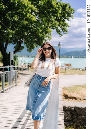 Elegant woman in denim skirt walking though the little bridge and smile. Stylish female 104615162