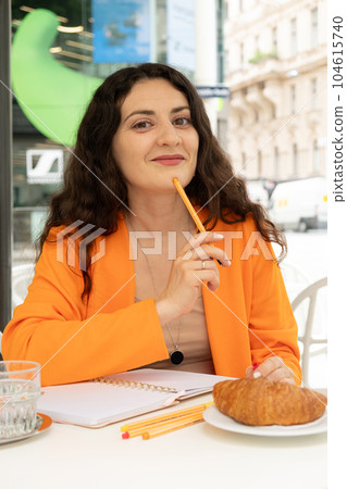 Beautiful young woman in a cafe sitting and writing with a pen in a notebook. Plans for the day, wish list, life diary 104615740