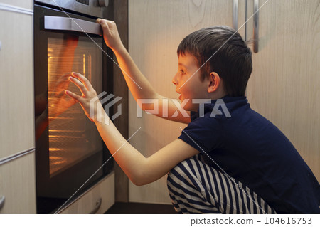 A child is sitting near the oven in the kitchen and waiting. A child is sitting near the oven in the kitchen and waiting. 104616753