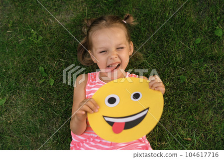 Crazy funny girl makes faces showing her tongue, doing the same as the smile face in the picture Crazy funny girl makes faces showing her tongue, doing the same as the smile face in the picture 104617716