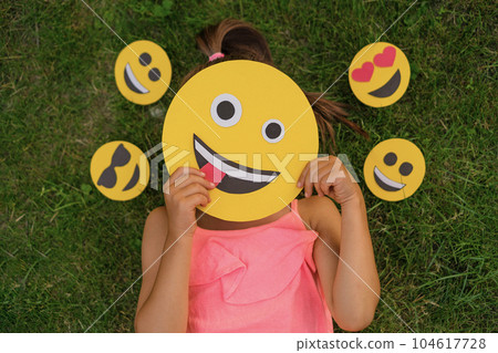 A woman hides her face behind emojis making faces. A variety of emoticons reflecting the emotional state 104617728