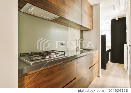 a modern kitchen with wood cabinets and black countertops on the wall behind it is an open door that leads to another room a modern kitchen with wood cabinets and black countertops on the wall behind it is an open door that leads to another room 104624118