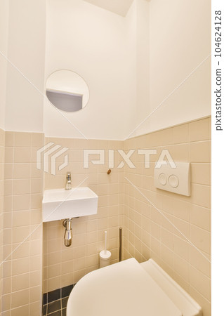 a white toilet and sink in a small bathroom with beige tiles on the walls, there is a mirror above it a white toilet and sink in a small bathroom with beige tiles on the walls, there is a mirror above it 104624128