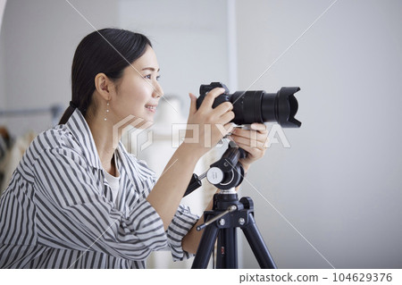 一位女攝影師正在操作架在三腳架上的相機。 一位女攝影師正在操作架在三腳架上的相機。 104629376