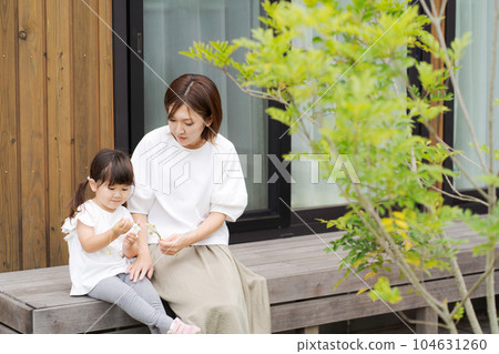 Photo of a parent and child sitting on a wooden deck 104631260