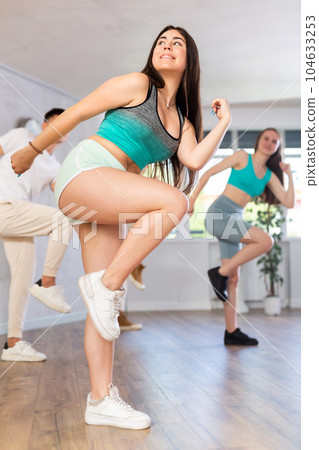 Girl teen perform choreographic exercise and teach energetic waacking dance with friends Girl teen perform choreographic exercise and teach energetic waacking dance with friends 104633253