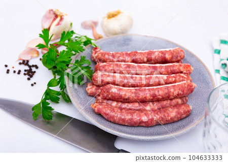 Traditional spanish dish. Longaniza, pork sausage on plate with herbs and cutlery 104633333