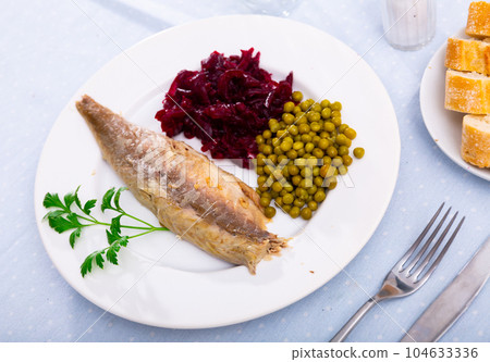 Slices herring fish with canned green peas, beetroot, decorated by mint served on plate with bread and cutlery Slices herring fish with canned green peas, beetroot, decorated by mint served on plate with bread and cutlery 104633336
