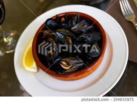 Steamed mussels with garlic sauce and lemon in clay bowl Steamed mussels with garlic sauce and lemon in clay bowl 104633975