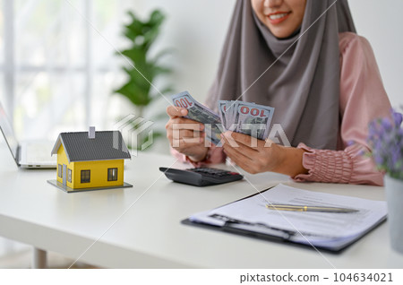 Young real estate agent counting and calculating her income and commision Young real estate agent counting and calculating her income and commision 104634021
