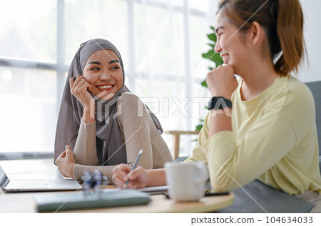 Young muslim woman chatting with her friend in the living room Young muslim woman chatting with her friend in the living room 104634033