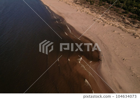 Drone aerial view of waves sea ocean coast. Beach and dunes dark calm sea waves nature landscape captured with drone. Tourism Drone aerial view of waves sea ocean coast. Beach and dunes dark calm sea waves nature landscape captured with drone. Tourism 104634073