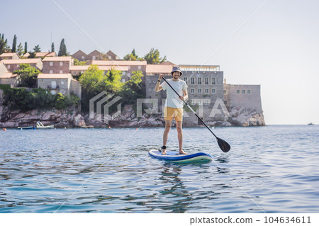 Young men Having Fun Stand Up Paddling in blue water sea near st stefan island in Montenegro. SUP 104634611