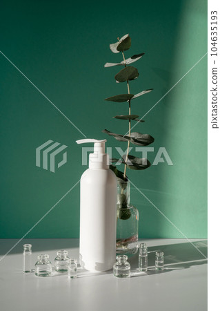 Eucalyptus and jars of cosmetics on a green background. Eucalyptus and jars of cosmetics on a green background. 104635193