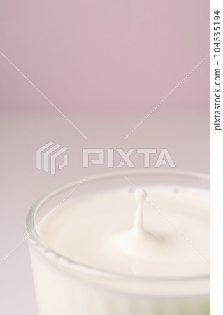 Milk drips into a transparent faceted glass. Milk drips into a transparent faceted glass. 104635194