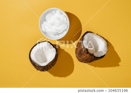 Two halves of coconut and coconut oil in a bowl. Two halves of coconut and coconut oil in a bowl. 104635196