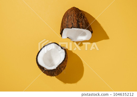 Two halves of coconut on a bright yellow background. 104635212