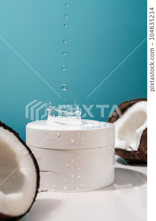 Two halves of coconut and a jar of cosmetics on a blue background with water drops. 104635214