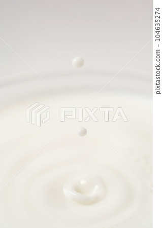 Milk drips into a transparent faceted glass. 104635274