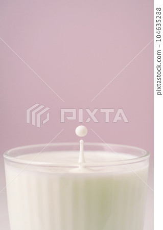 Milk drips into a transparent faceted glass. Milk drips into a transparent faceted glass. 104635288