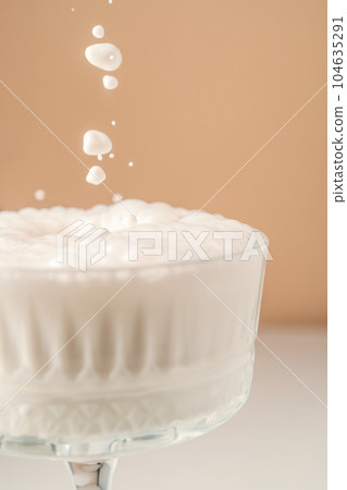 Milk pours into a beautiful crystal glass and splashes around. 104635291