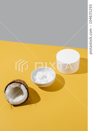 Half a coconut, coconut oil and a jar of coconut cream on a yellow background. 104635293