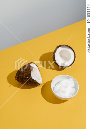 Two halves of coconut and coconut oil in a bowl. Two halves of coconut and coconut oil in a bowl. 104635324