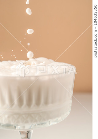Milk pours into a beautiful crystal glass and splashes around. 104635350