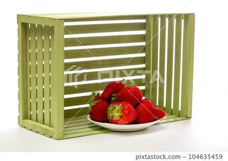Red ripe strawberries in a plate near a box 104635459