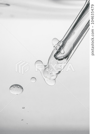 Pipette with cosmetic product in water with bubbles. 104635479