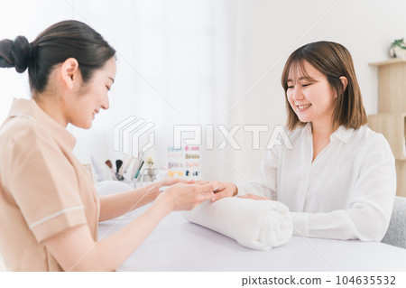 Manicurist and woman counseling hands at nail salon Manicurist and woman counseling hands at nail salon 104635532