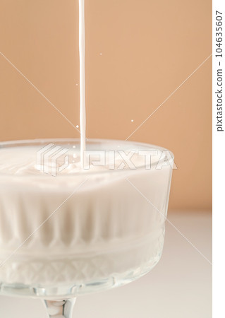 Milk pours into a beautiful crystal glass and splashes around. 104635607
